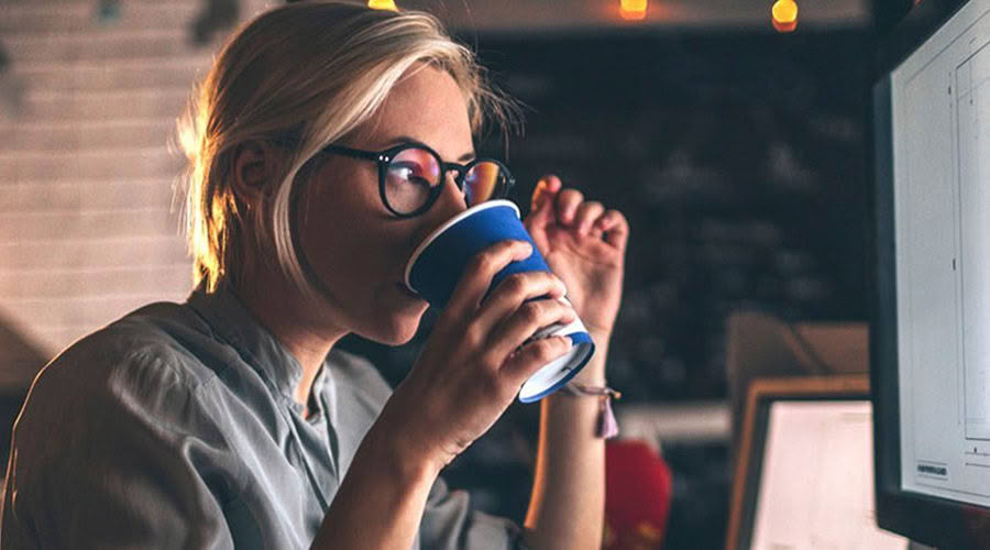 women working at computer drinking coffee